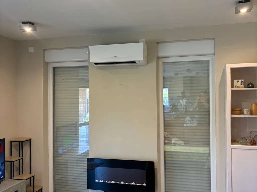De afgewerkte binnenunit hangt strak tegen de muur van de woonkamer, boven de sfeerhaard.